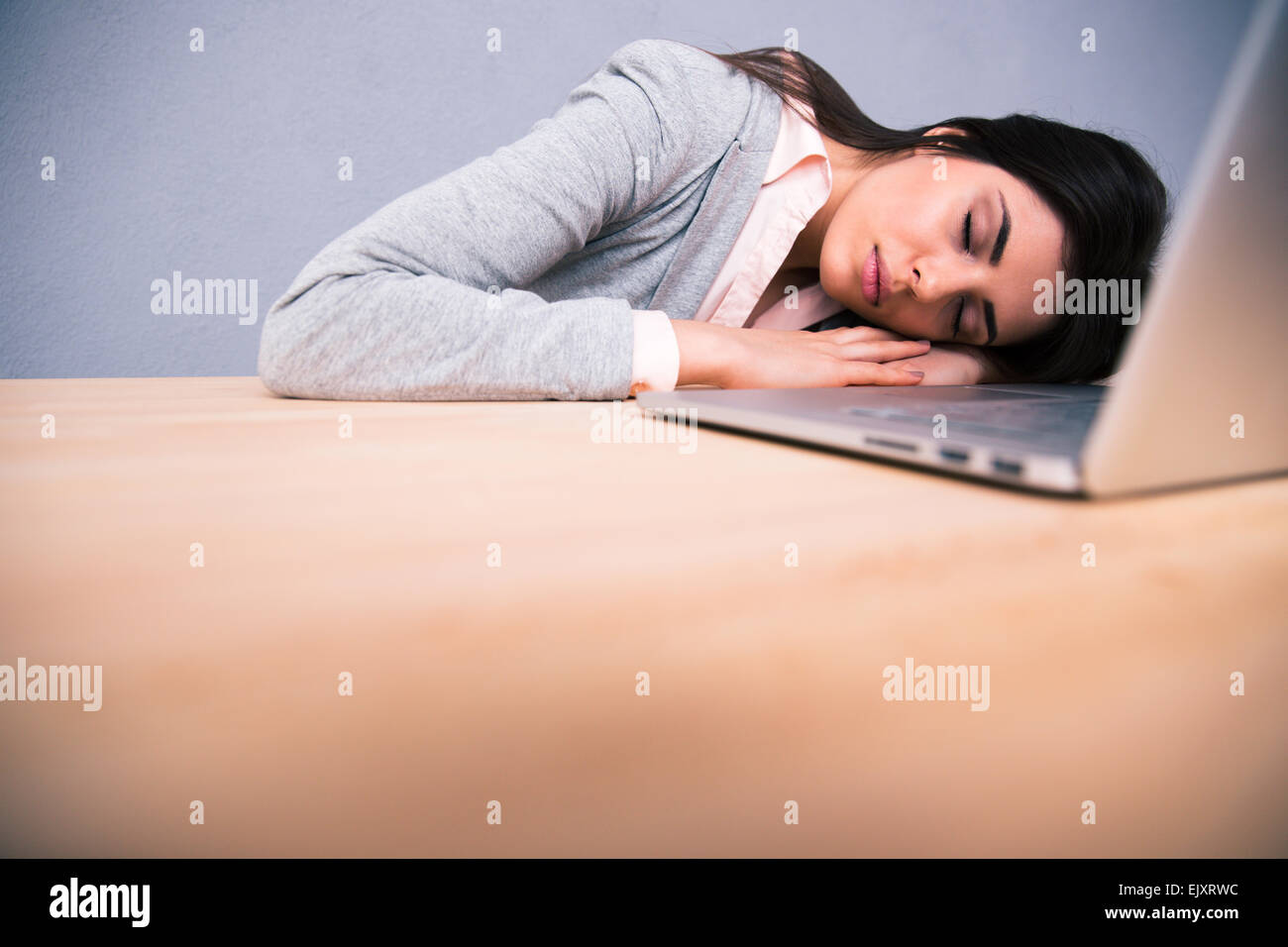 Junge hübsche Frau mit Laptop auf dem Tisch schläft Stockfoto