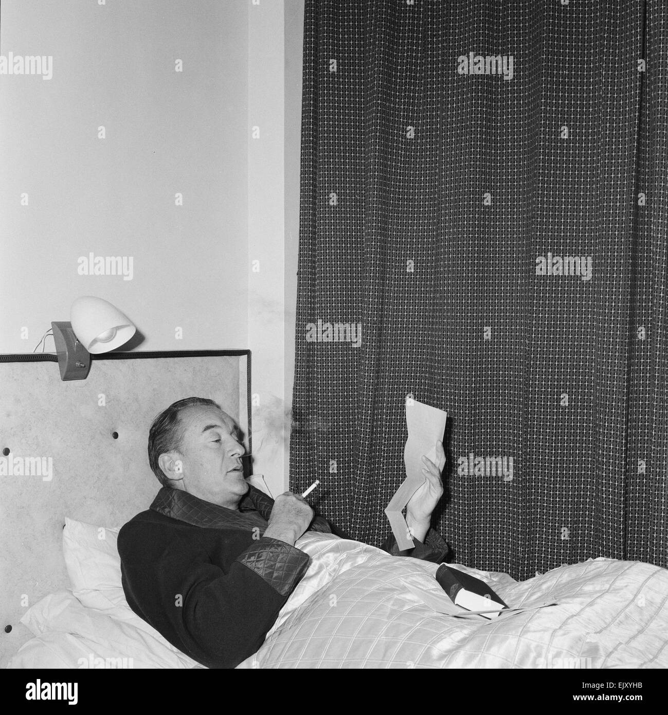 Schauspieler George Sanders setzt sich in seinem provisorischen Bett in Elstree Studios, wo er derzeit "Blaubärten zehn Flitterwochen", 7. November 1959 filmt.    Der Film basiert auf den realen Verbrechen des französischen Serienmörders Henri Landru.      Lokalen Caption *** Rauchen im Bett Stockfoto
