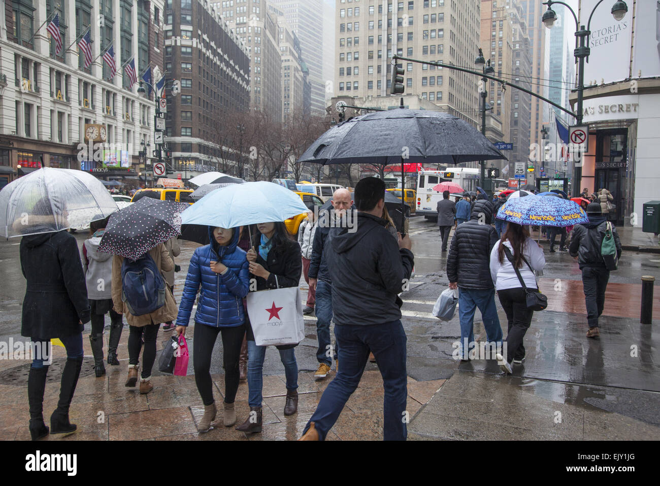 Die Straße bleibt an einem regnerischen Tag in Midtown Manhattan mit Sonnenschirmen, beschäftigt. Stockfoto