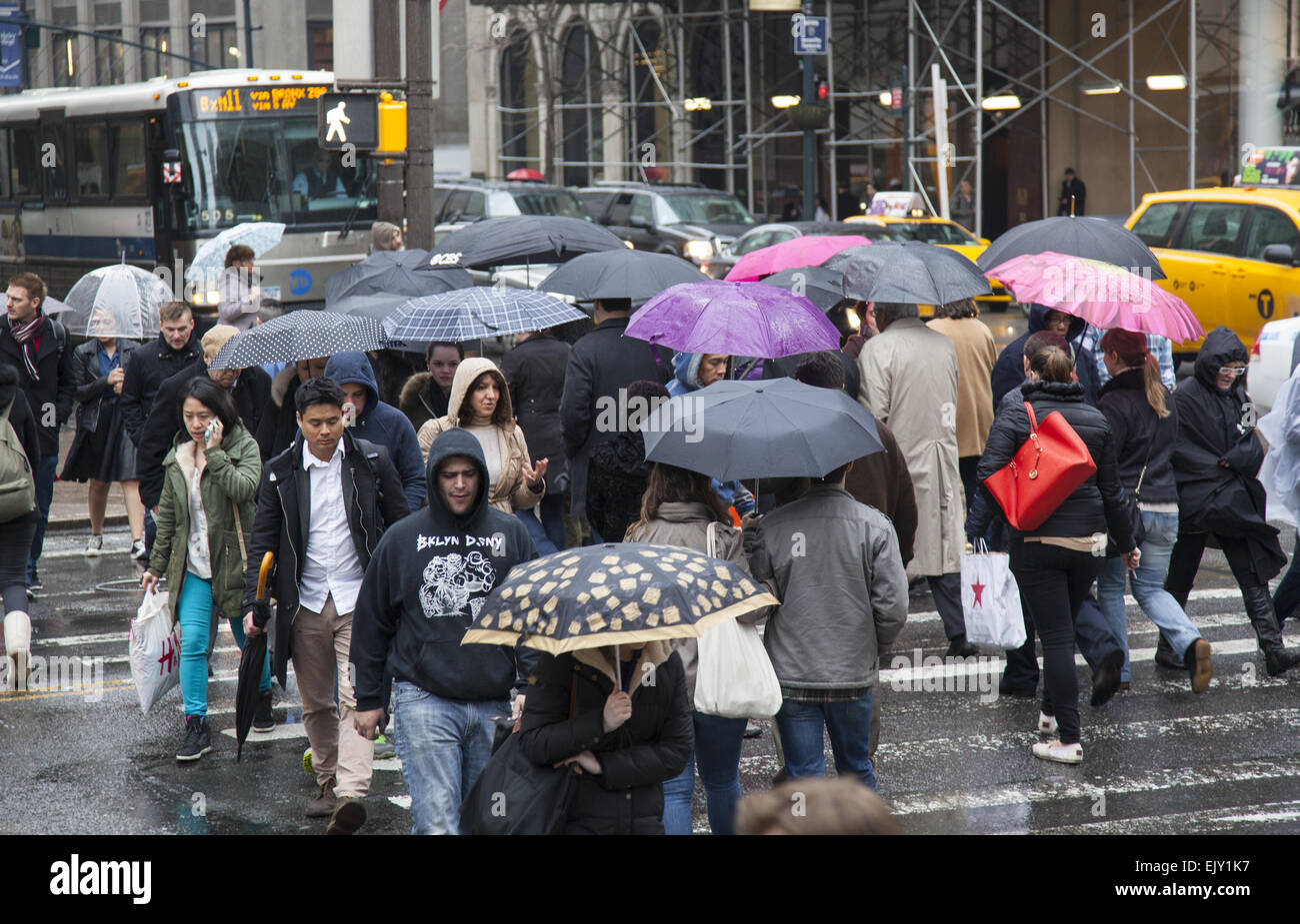 Die Straße bleibt an einem regnerischen Tag in Midtown Manhattan mit Sonnenschirmen, beschäftigt. Stockfoto
