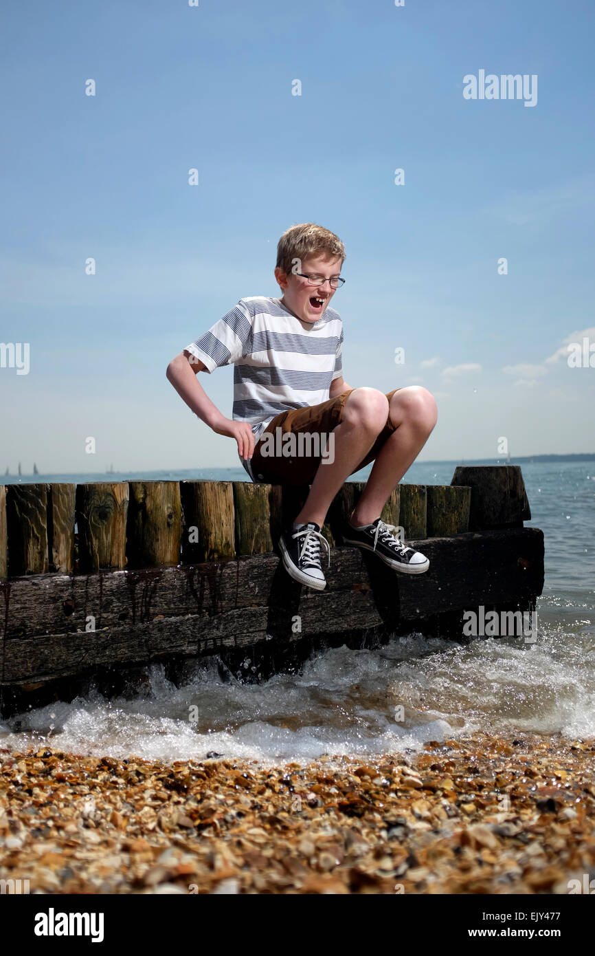 Ein Teenager lacht als die Meer-Spritzer an den Füßen an einem britischen Strand Stockfoto