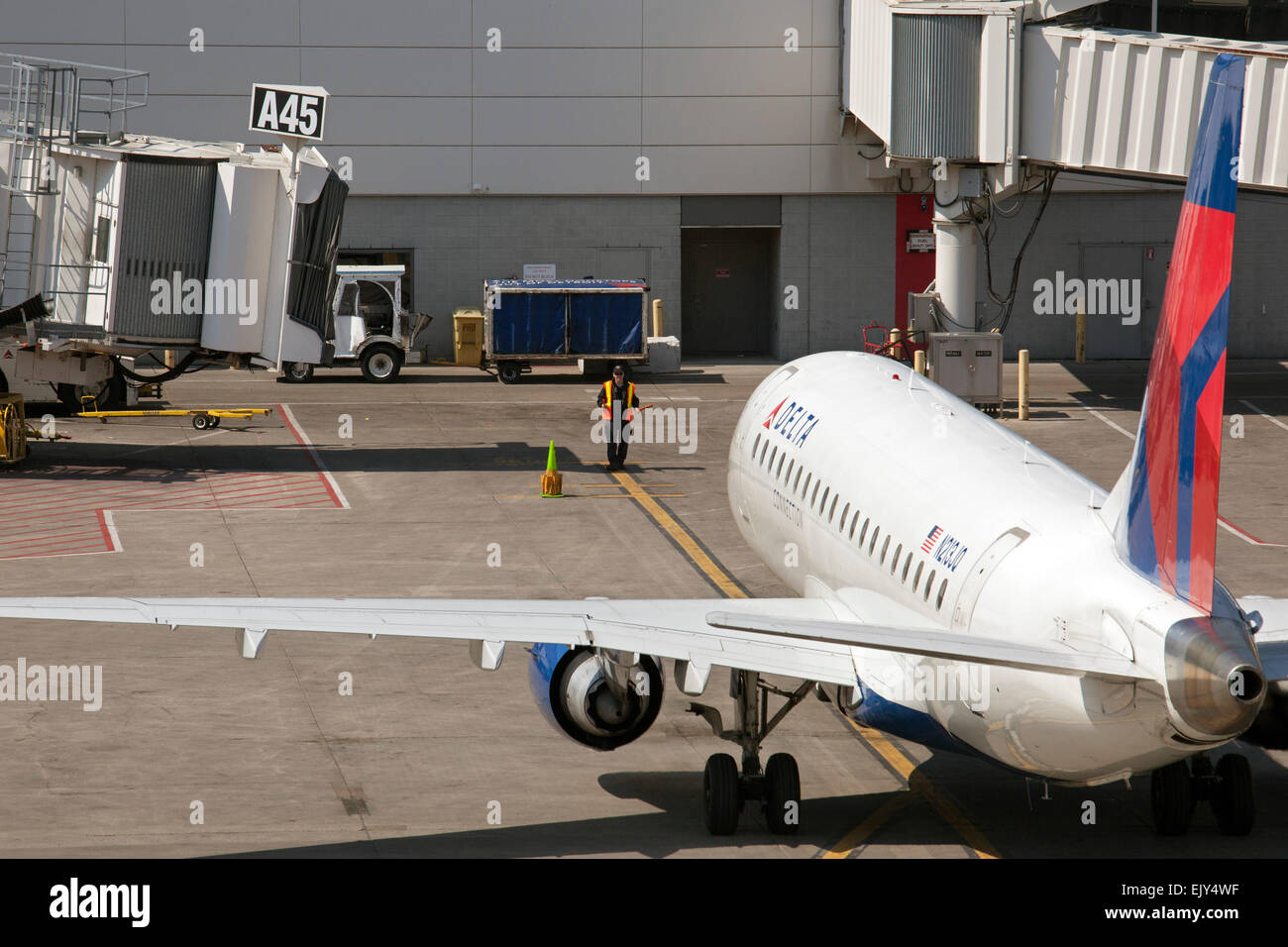 Romulus, Michigan - ein Boden-Crew-Mitglied führt ein Verkehrsflugzeug, das Tor am Detroit Metro Airport McNamara Terminal. Stockfoto