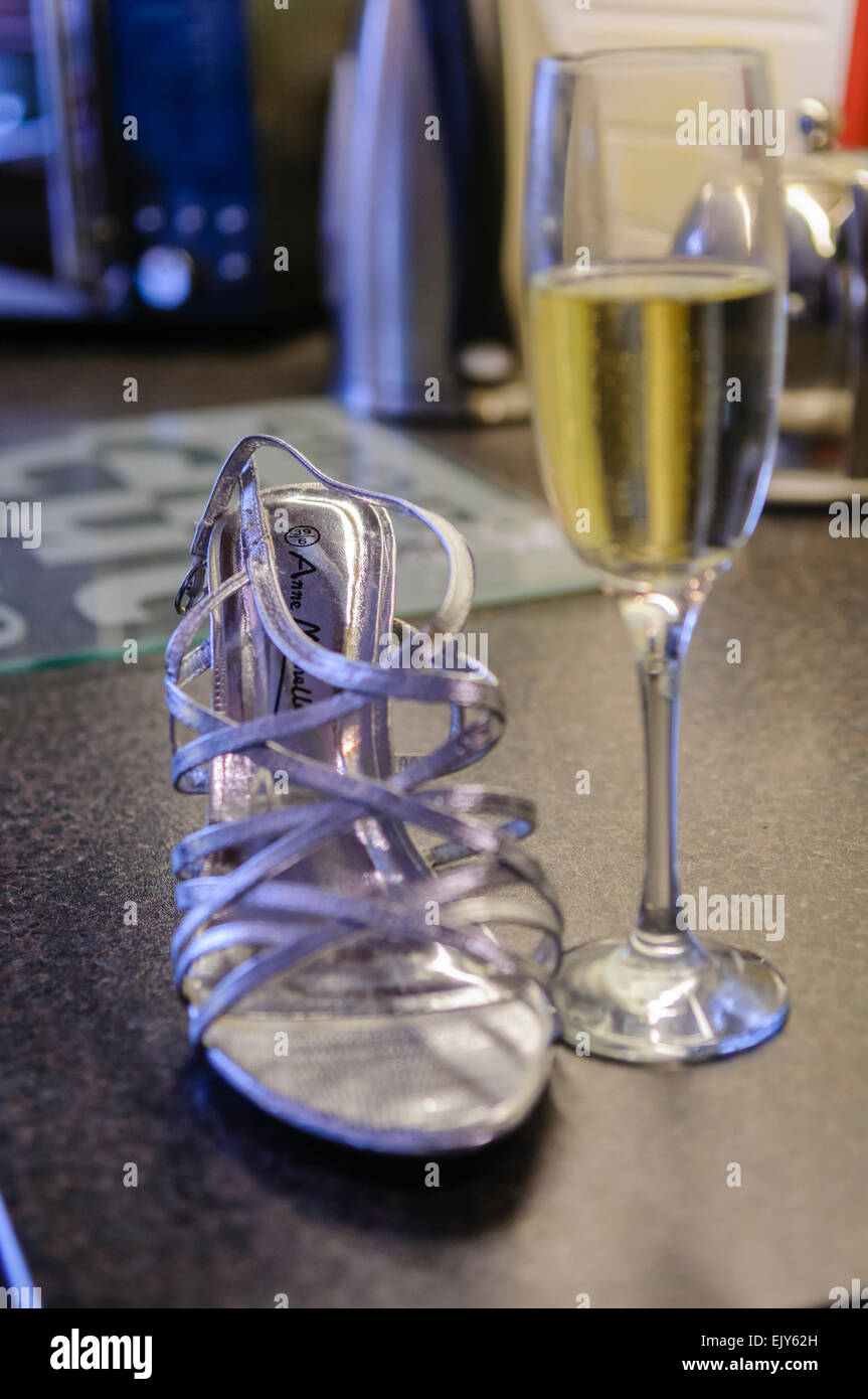 Silberne Hochzeit einer Braut Schuh und ein Glas Champagner sitzen auf einem Tisch, während Sie bereit erhält Stockfoto
