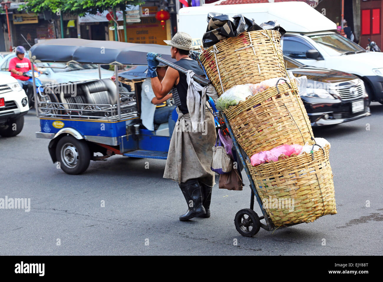 Arbeiter tragen Körbe von Produkten auf der Straße in Chinatown in Bangkok, Thailand Stockfoto