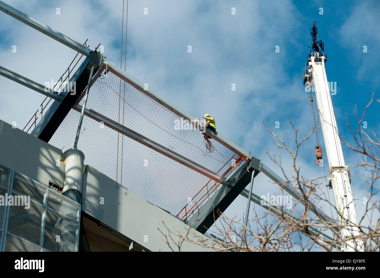 Workman Befestigung Sicherheit Netz auf dem Dach des Etihad Stadium,  Südtribüne Erweiterungsprojekt, Manchester, England, UK Stockfotografie -  Alamy