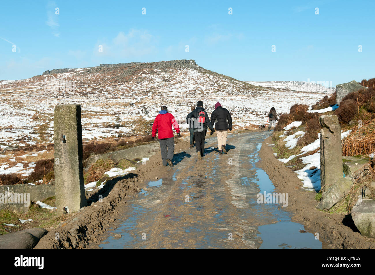 Wanderer auf einer schlammigen Strecke mit Carl Wark Hügel in der Ferne. In der Nähe von Hathersage, Peak District, Derbyshire, England, Vereinigtes Königreich Stockfoto