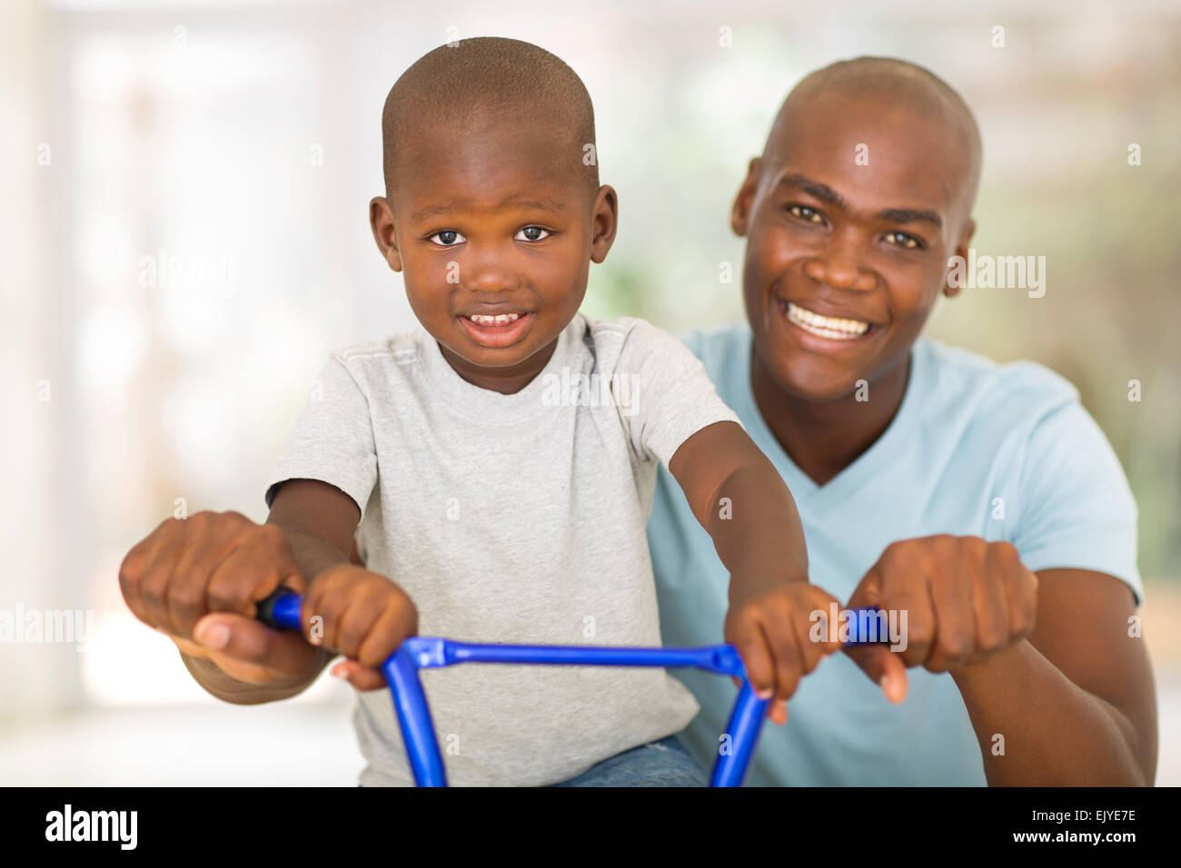 Portrait des afrikanischen Mann hilft Sohn Fahrrad fahren Stockfoto