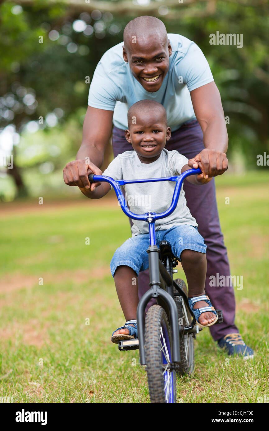 fröhliche afrikanische amerikanische Mann Lehre Sohn Radfahren im park Stockfoto