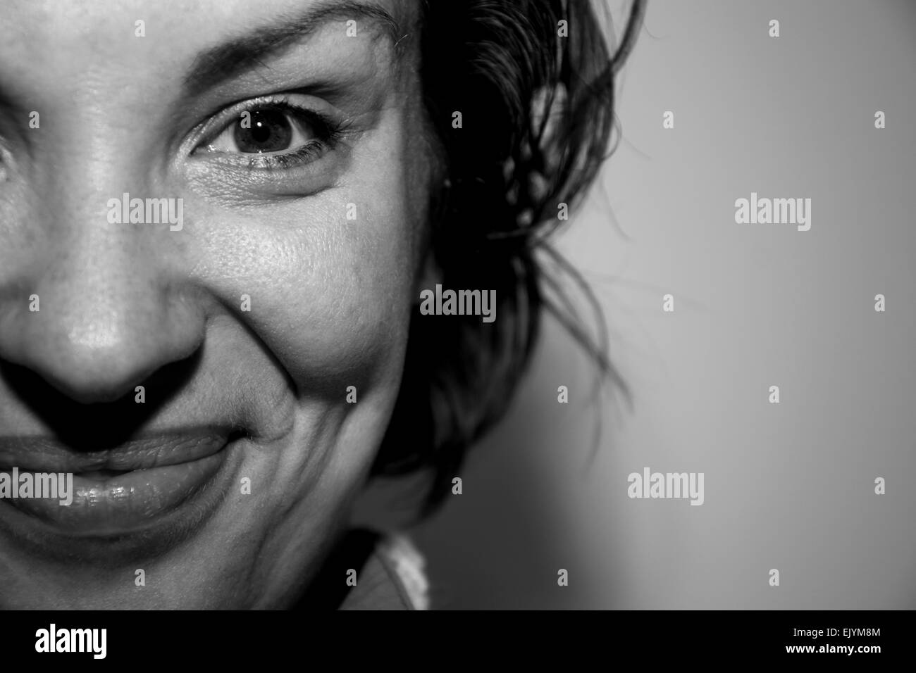 Porträt einer hübschen jungen Frau lächelnd in Monochrom drinnen hautnah Stockfoto