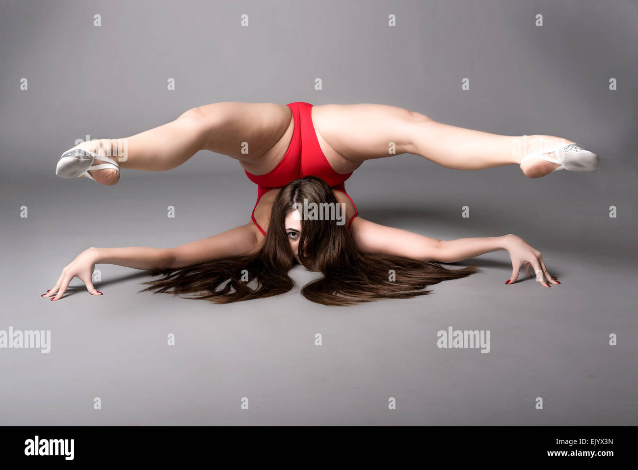 Junge weibliche Contortionist, auf dunklem Hintergrund Stockfoto