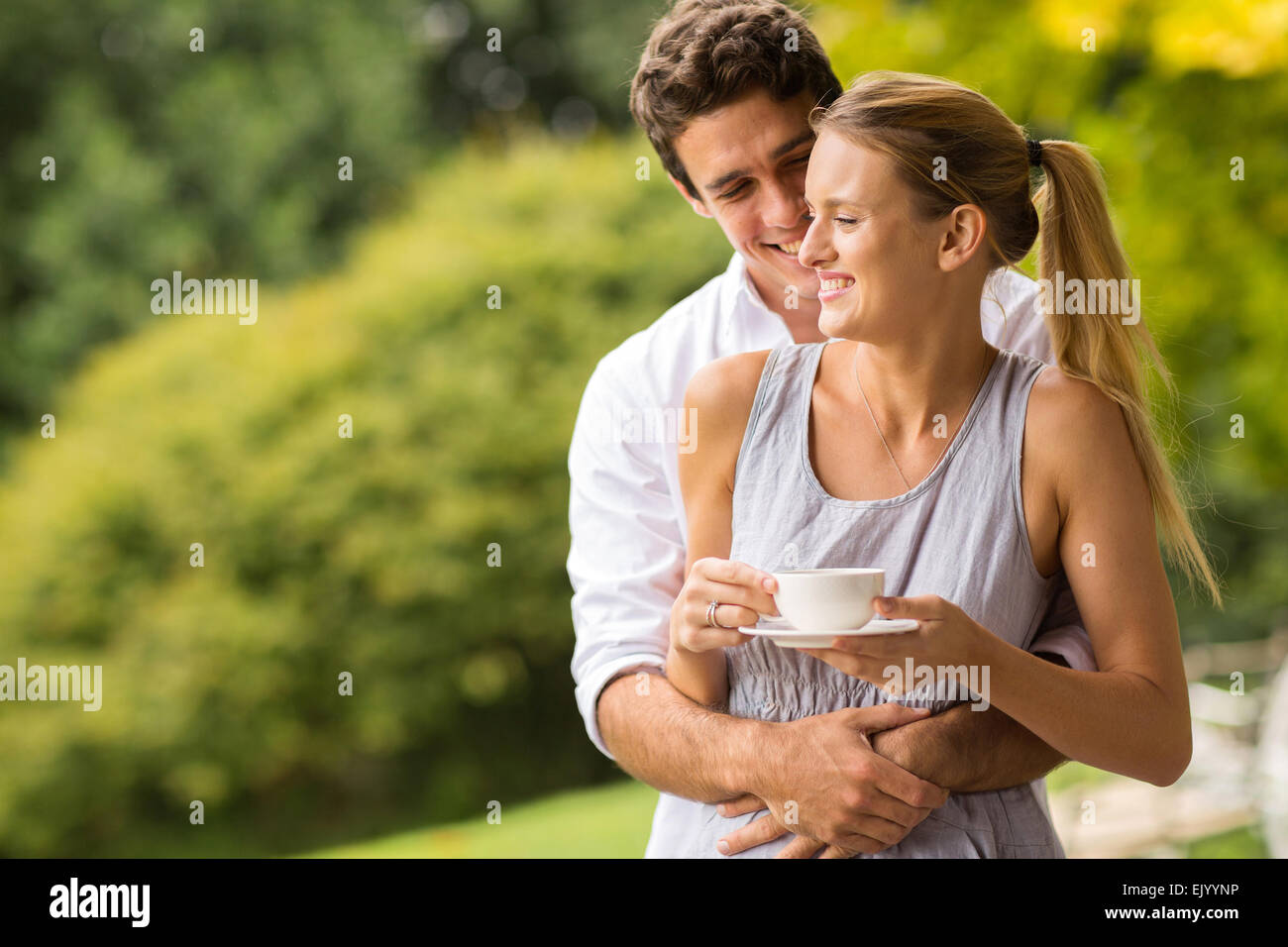glückliche junge Mann umarmt Frau im freien Stockfoto