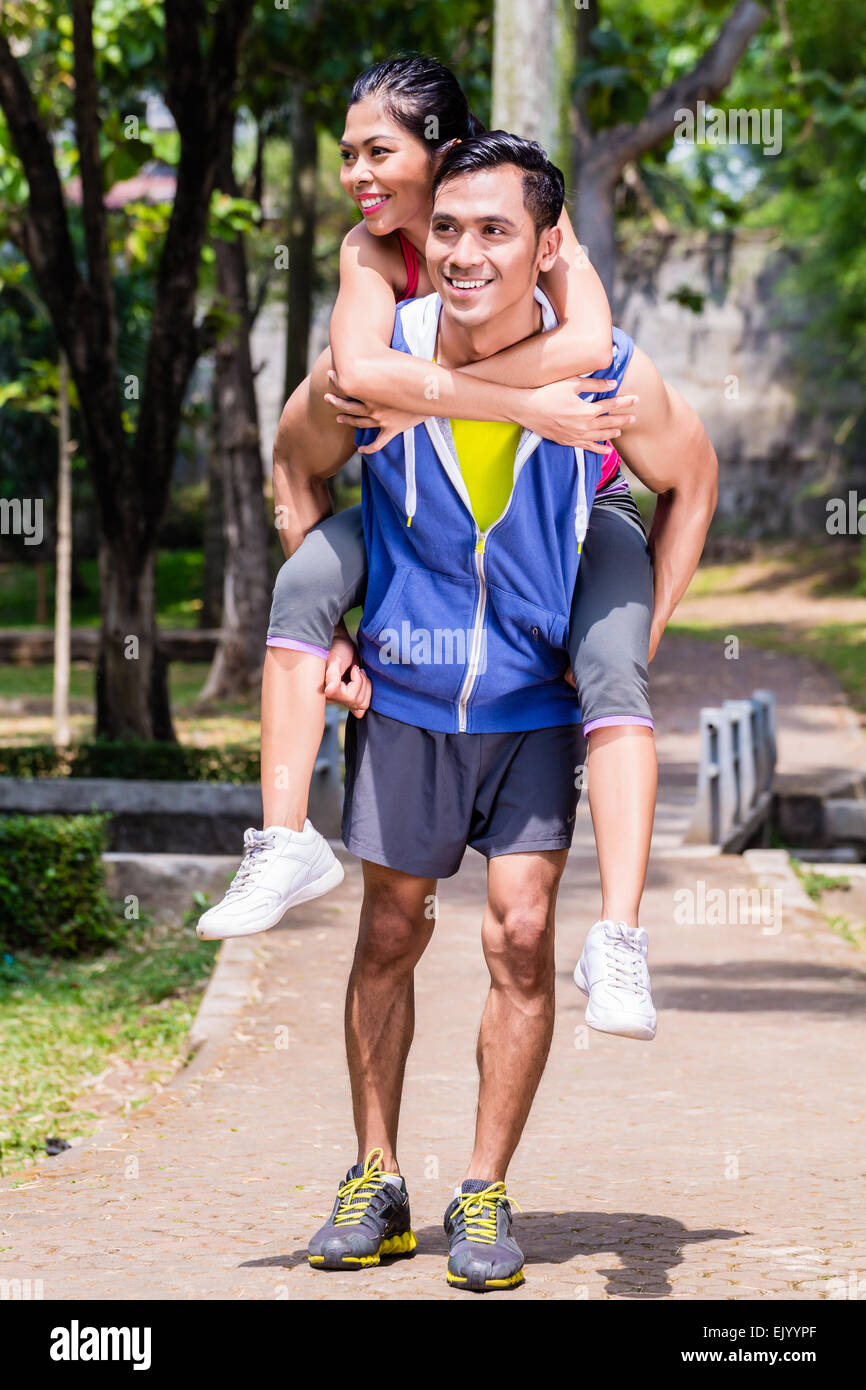 Asiatischen Mann mit seiner Freundin Piggyback für Sport in einer Pause während seiner Sport-Ausbildung Stockfoto