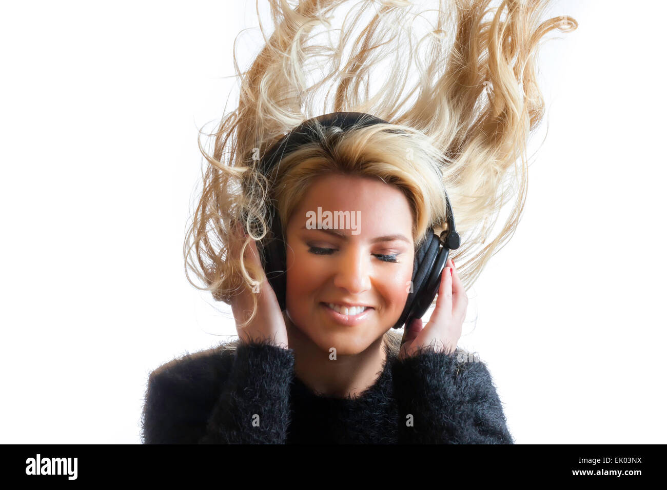 Eine hübsche, Blonde, Latina Mädchen rocken und warf ihr Haar beim großen schwarzen Studiokopfhörer anhören. Isoliert auf einem Stockfoto