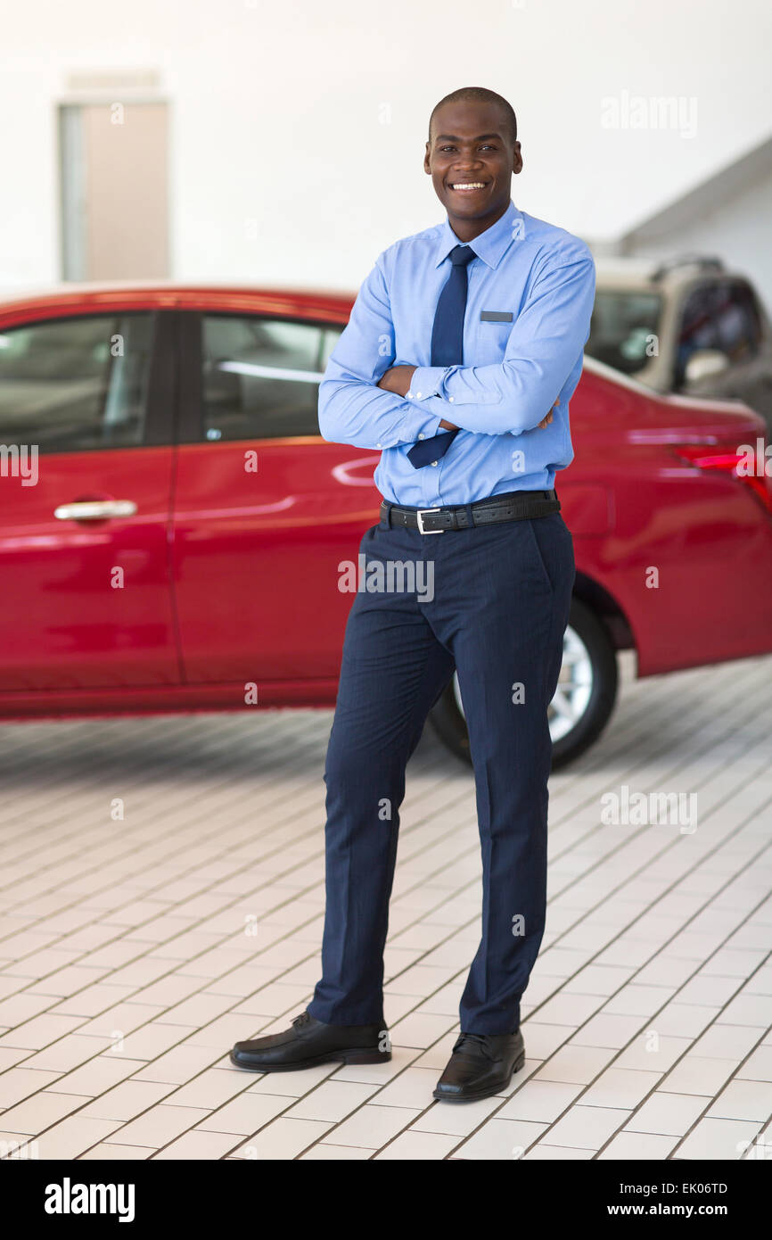 gut aussehende afrikanische Fahrzeug Verkäufer mit Arme gekreuzt im Showroom stehen Stockfoto