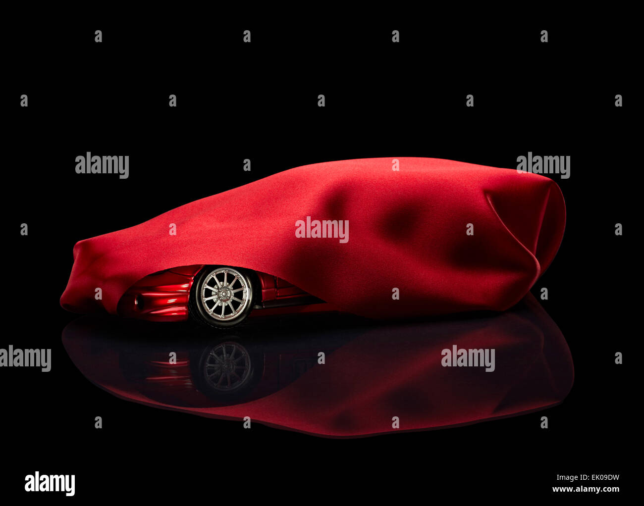 Nahaufnahme eines neuen Autos versteckt unter rotem Einband auf schwarzem Hintergrund Stockfoto