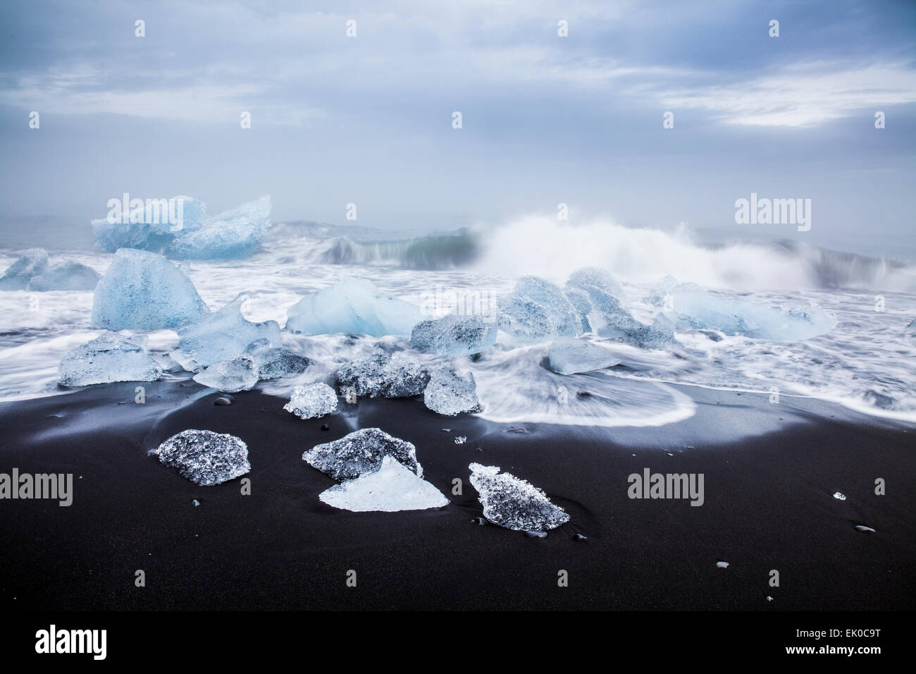 Blick auf Brocken von Eisbergen und Meeresbrandung am schwarzen Sandstrand in Jökulsárlón, Island Stockfoto