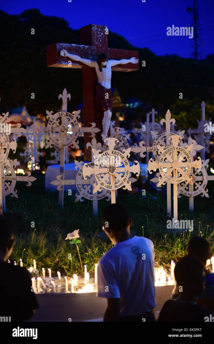 Larantuka, Indonesien. April 2015. Die Menschen beten nach einer Massenfeier in der nahe gelegenen Domkirche bei der Karfreitagsfeier in Larantuka, Flores Island, Indonesien, auf einem Friedhof. Tausende von Menschen, darunter auch aus anderen Städten und Ländern, nehmen an einer ganzen Woche an Feierlichkeiten zur Feier der Karwoche in der Kleinstadt Larantuka Teil, einer der einflussreichsten Städte Indonesiens in Bezug auf die Tradition der Katholiken. Stockfoto