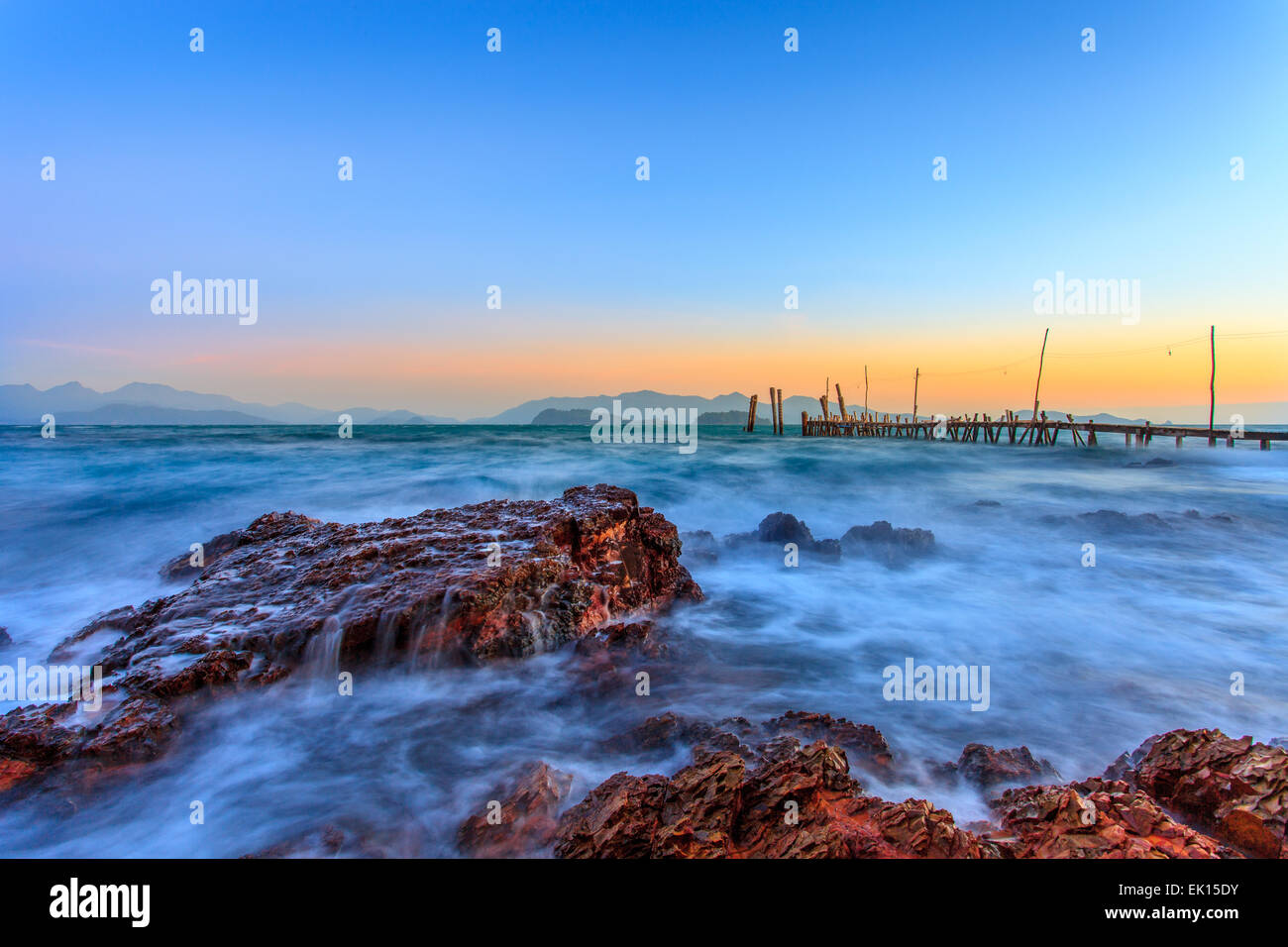 Ko-Weg Pier bei Sonnenuntergang mit Felsen im Vordergrund Stockfoto