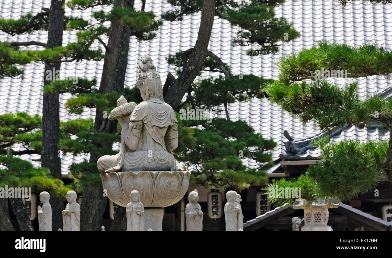 Statue der Göttin der Barmherzigkeit mit Pinien und Ziegeldach des Itsukushima-Schreins, Miyajima, Japan Stockfoto
