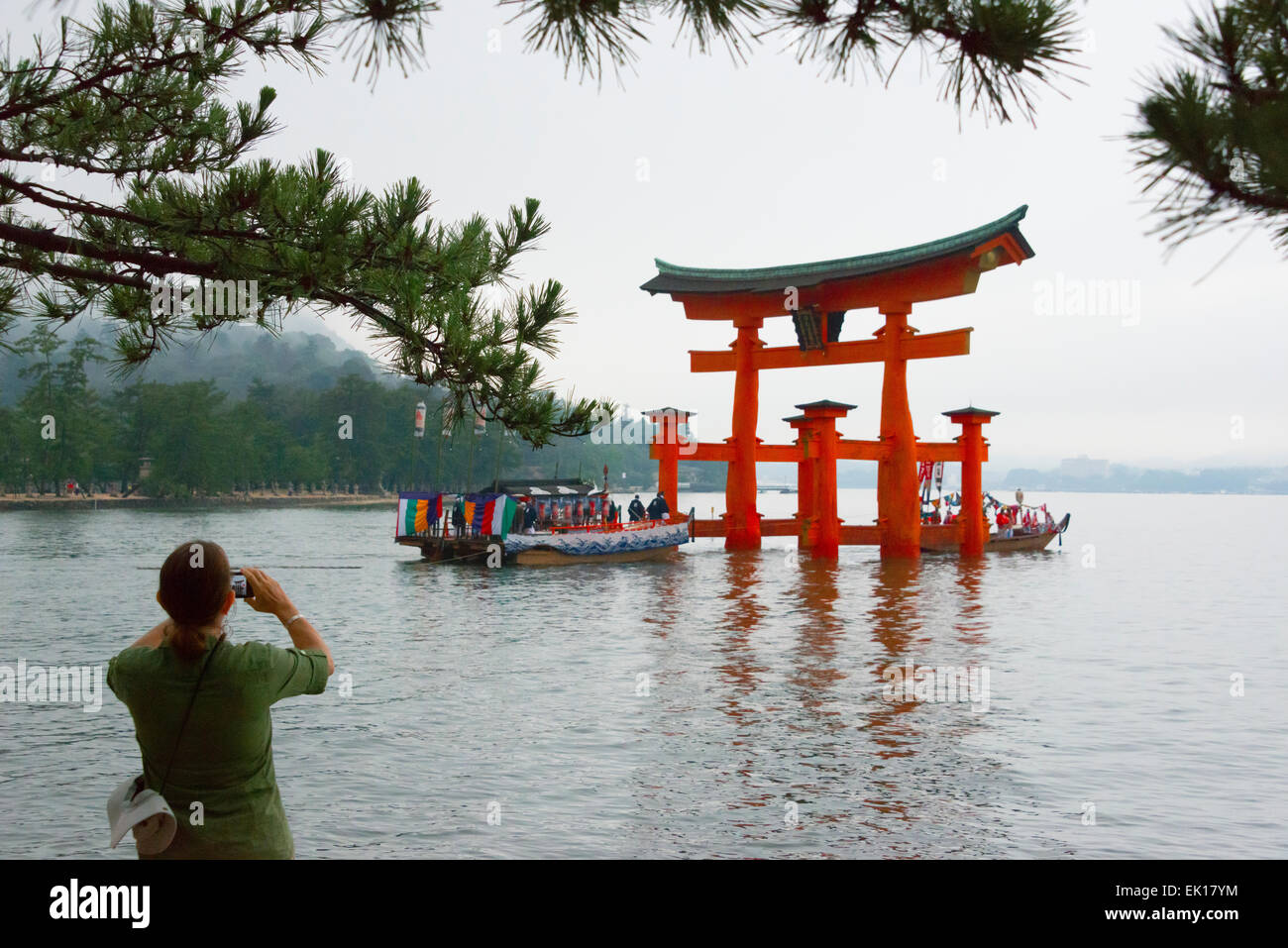 Touristen fotografieren Boot nähert sich Torii Tor des Itsukushima-Schrein während Kangen-Sai Festival, Miyajima, Japan Stockfoto