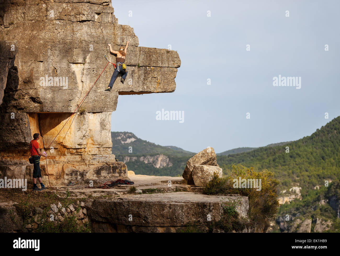 Junge Frau Klettern auf Felsen, männlichen Partner sichern Stockfoto