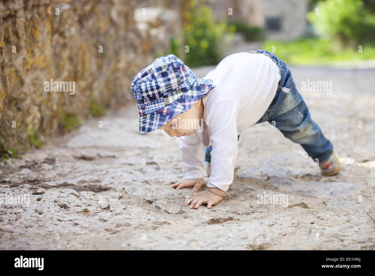 Niedlicher kleine Junge kriecht auf Stein gepflasterte Bürgersteig Stockfoto
