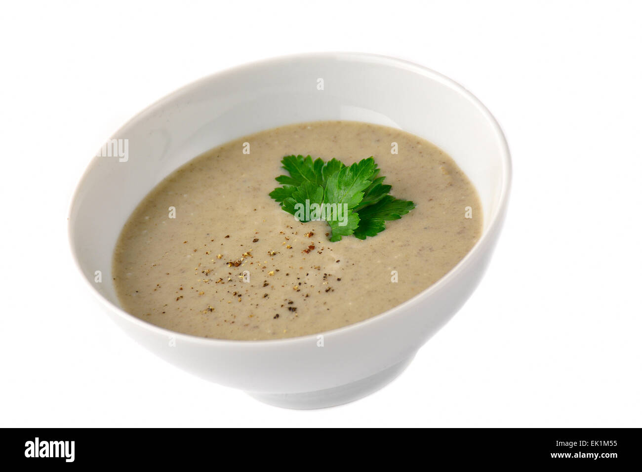 Champignon Cremesuppe in weiße Schüssel mit geriebenen Pfeffer und Petersilie garniert. Isoliert Stockfoto