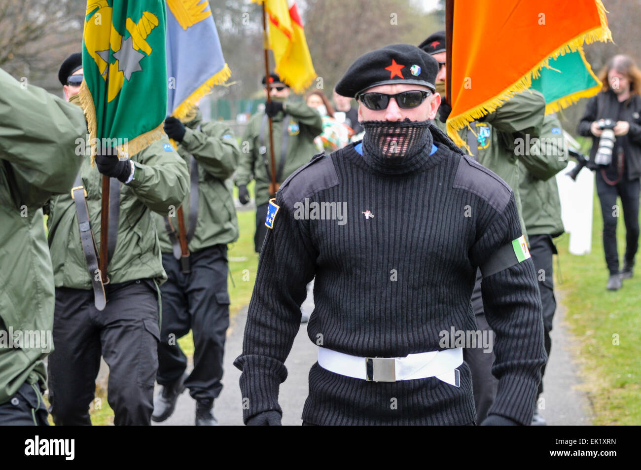 Belfast, Nordirland, Großbritannien. 5. April 2015. Ein Mann mit einem schwarzen paramilitärischen einheitliche, einschließlich dunkle Brille, Schal und Baskenmütze, führt die Farbe Partei der Irish Republican Socialist Party (eng mit der verbotenen Irish National Liberation Army angegliedert) Credit: Stephen Barnes/Alamy leben Nachrichten Stockfoto