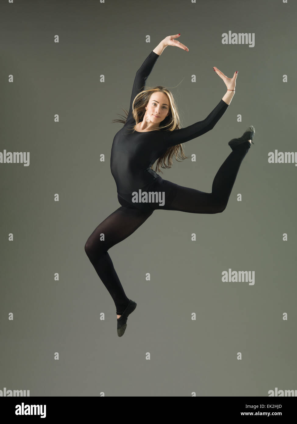 glückliche Tänzerin springen vor grauem Hintergrund Stockfoto