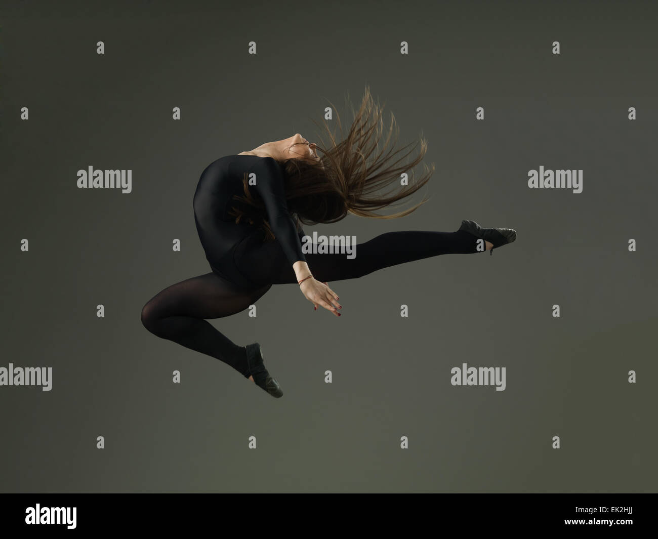 Tänzerin, die Durchführung von Hochsprung vor grauem Hintergrund Stockfoto