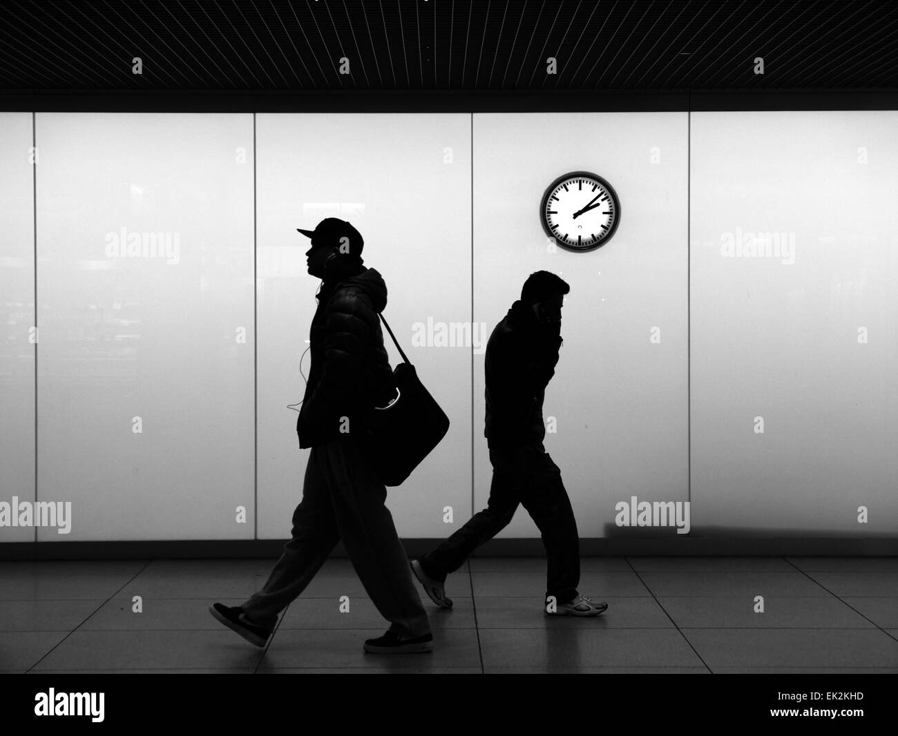 Urban City Pendler eilen unter Wanduhr pendeln. Moderne Pendler Musik hören oder im Gespräch mit smartphone Stockfoto