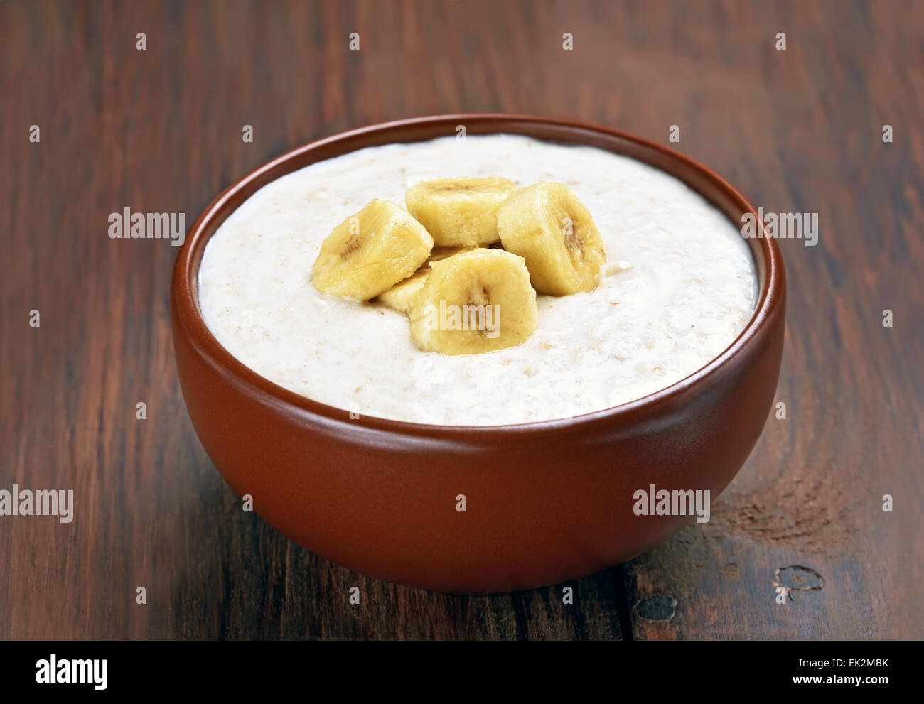 Brei Hafer mit Bananenscheiben auf Holztisch Stockfoto