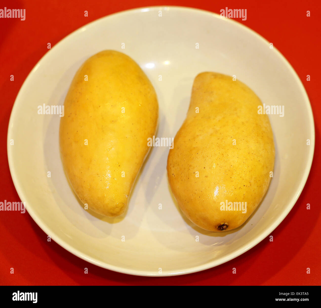 Zwei gelbe leckere Mango liegen auf einem Teller Stockfoto