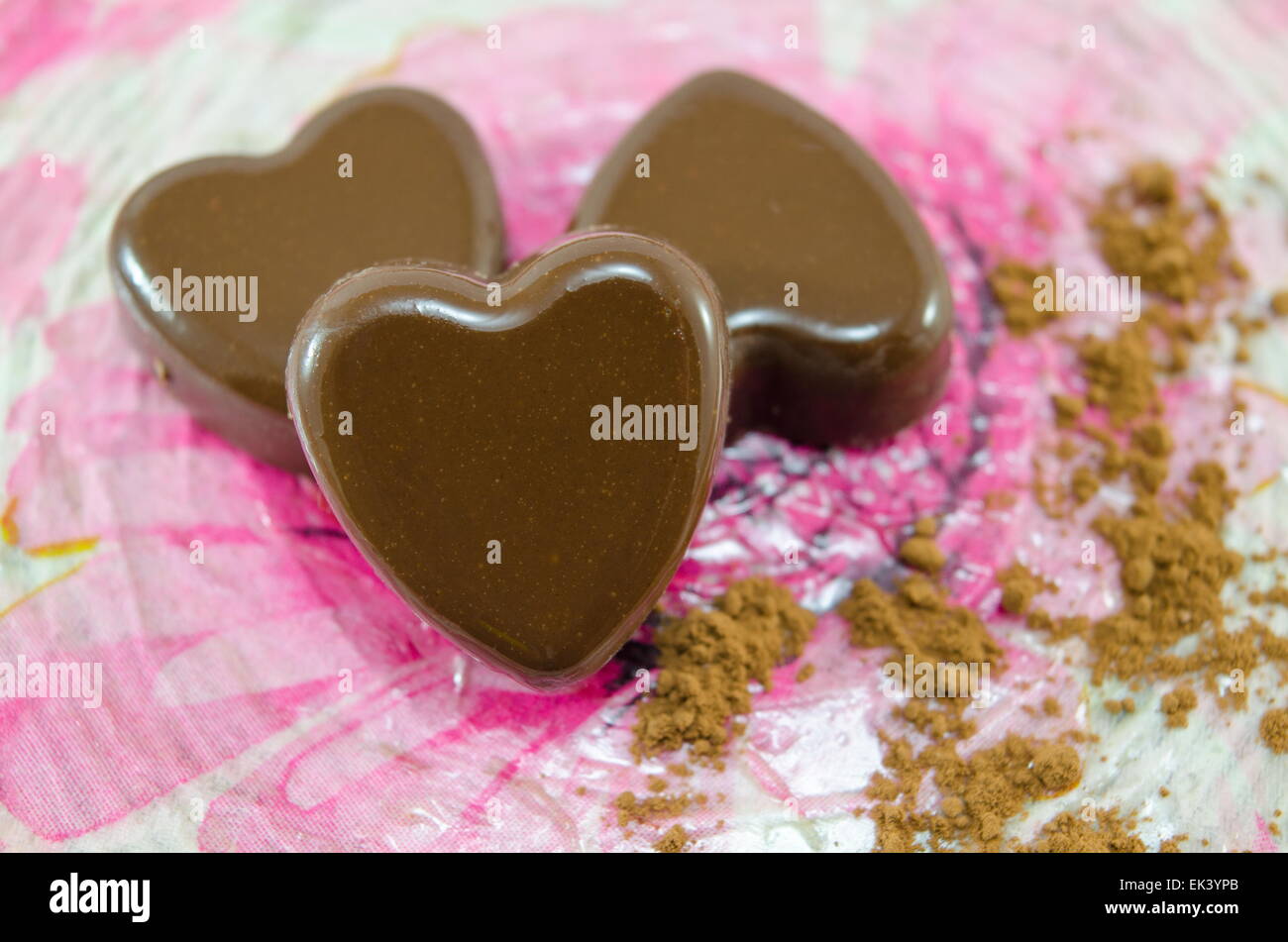 Herzförmige Pralinen auf einem Decoupage Teller mit Kakao Stockfoto