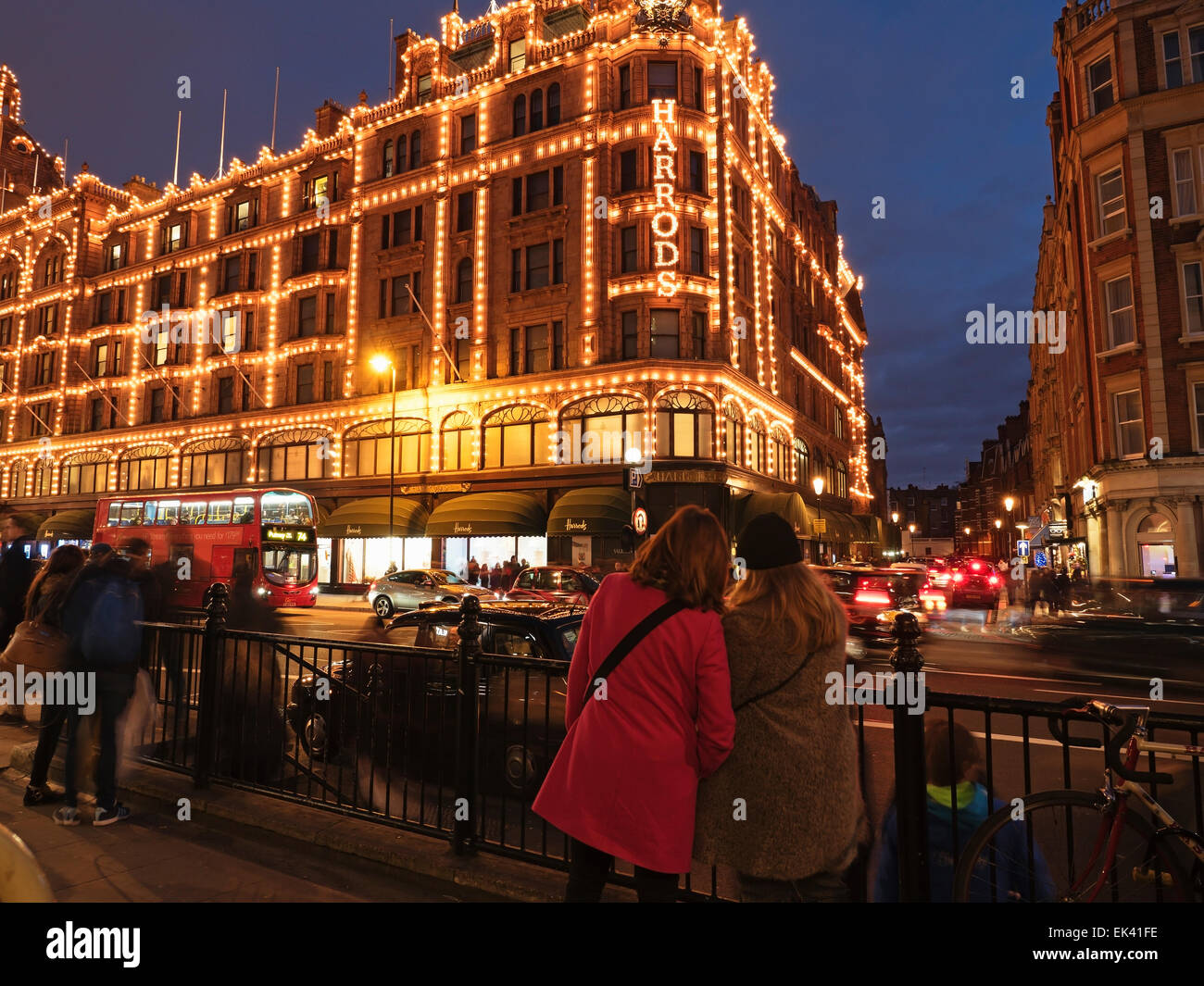 Touristen sehen das nachts beleuchtete Kaufhaus Harrods, Brompton Road, Knightsbridge, Royal Borough of Kensington und Chelsea, London, England Stockfoto