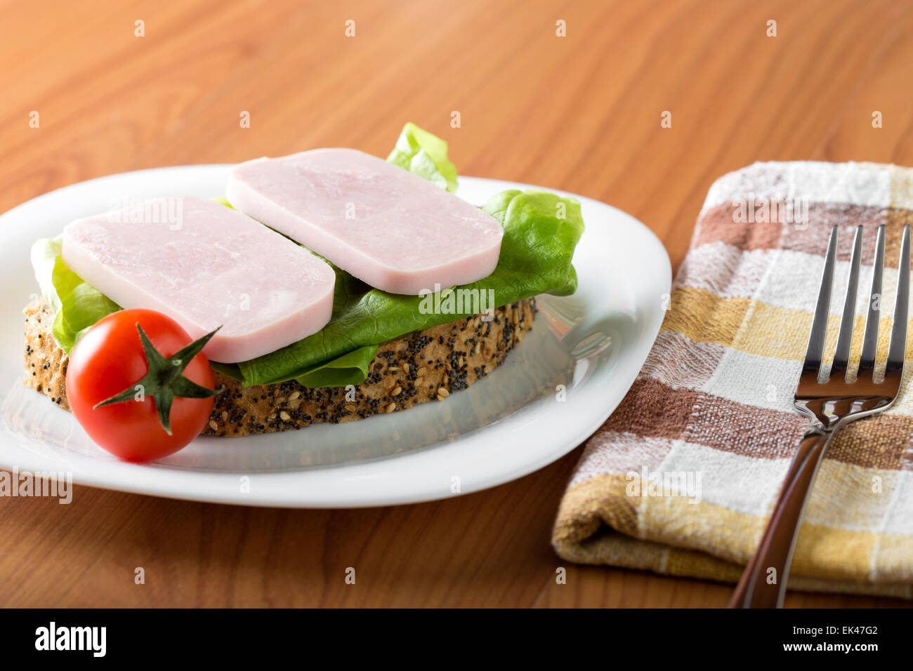 Zwei Scheiben Schinken mit Brot und Tomaten auf einem weißen Teller Stockfoto
