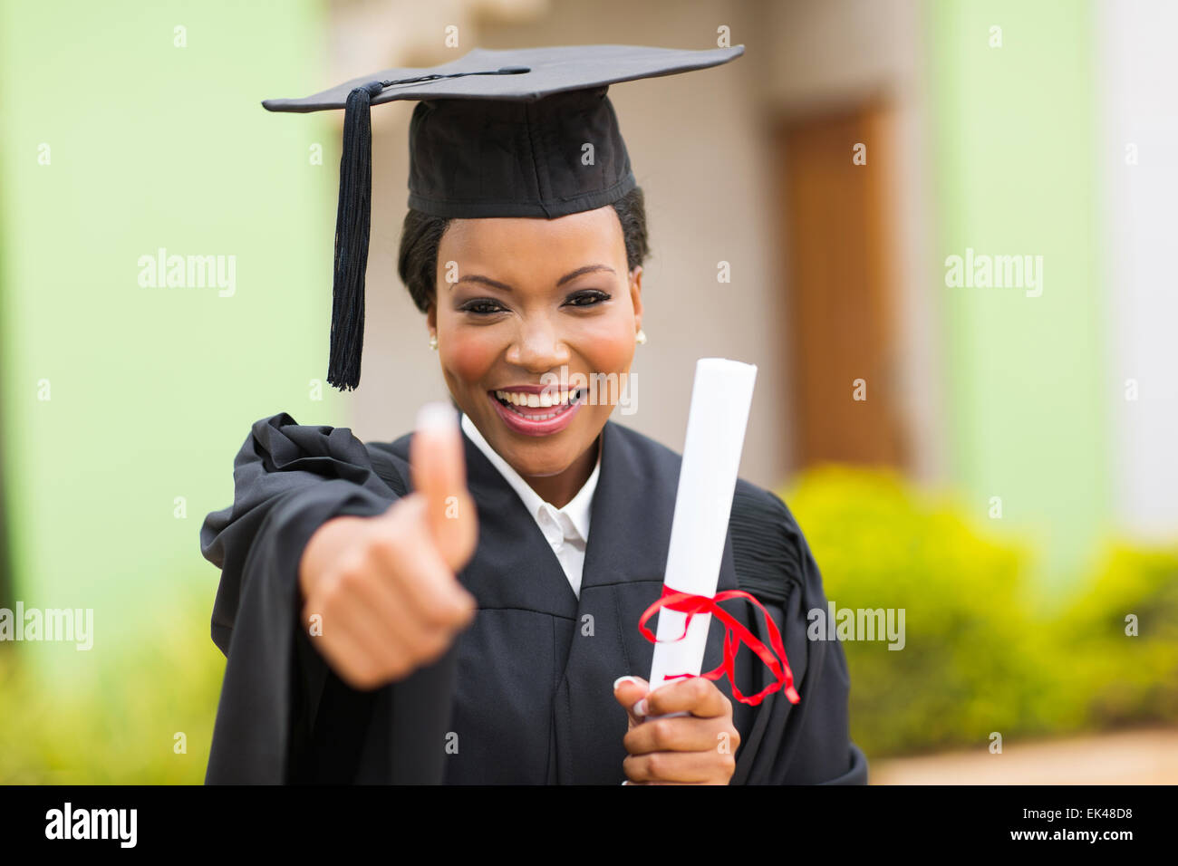 schöne afrikanische weibliche Absolventin Daumen aufgeben bei Abschlussfeier Stockfoto