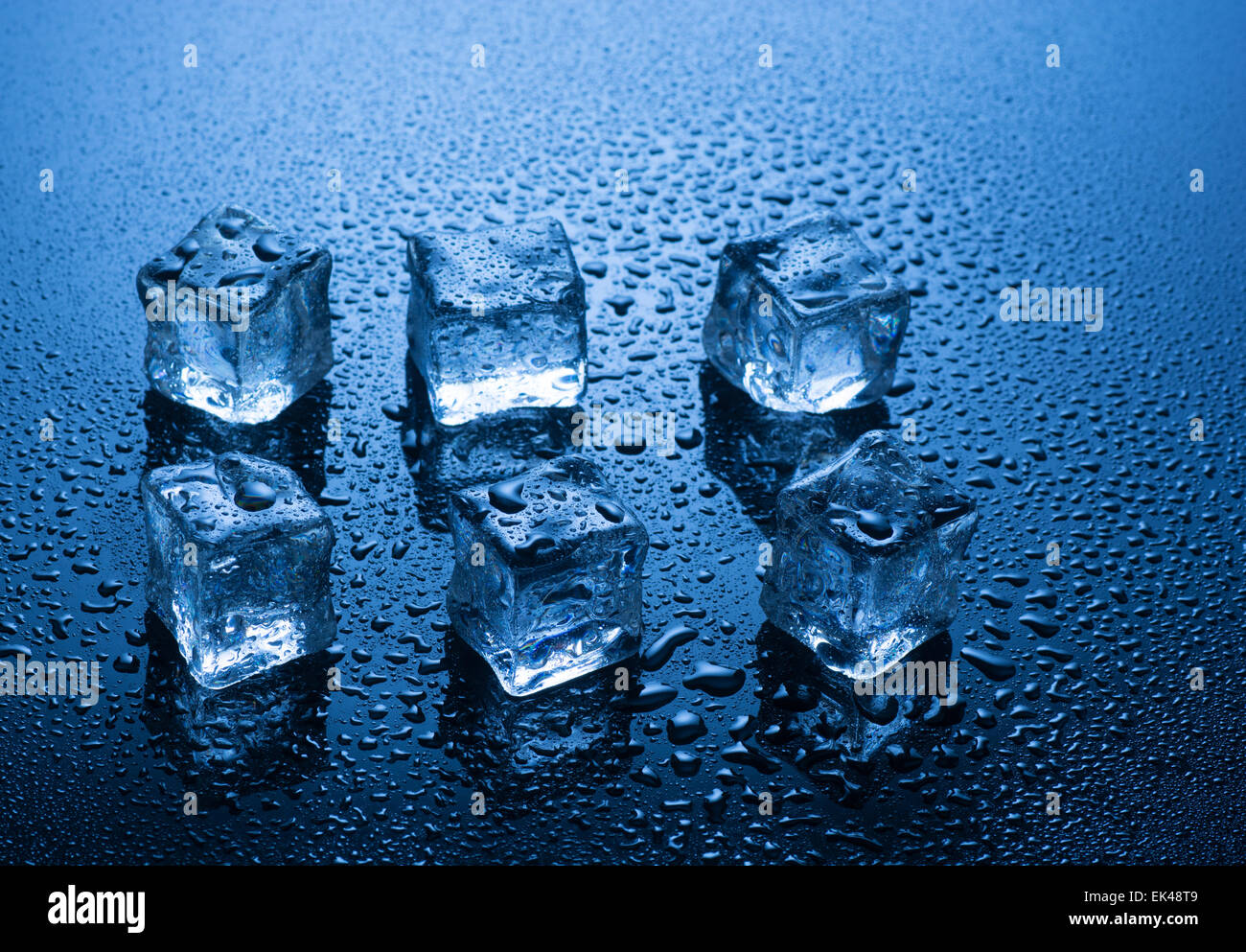 Eiswürfel mit Wasser fällt auf blauem Hintergrund Stockfoto