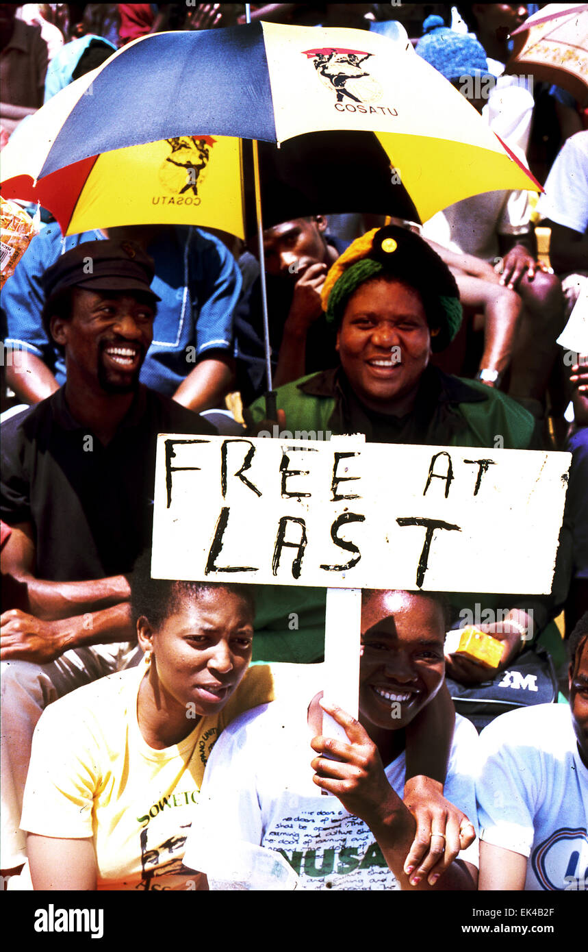 "Gebühr endlich" bezieht sich auf die Tatsache, dass Nelson Mandela endlich frei ist. Er wurde nach 27 Jahren Haft aus dem Gefängnis entlassen. Feierlichkeiten waren überall in Südafrika, seine Freiheit und der Weg zur Freiheit und Demokratie für Südafrika zu feiern statt. Einige der Zuschauer bei einer Kundgebung um Mandelas Freilassung halten ein Plakat zu feiern freie endlich und ein COSATU Regenschirm Wth Lächeln der Freude, Soweto, Johannesburg, 12.02.1990 Stockfoto