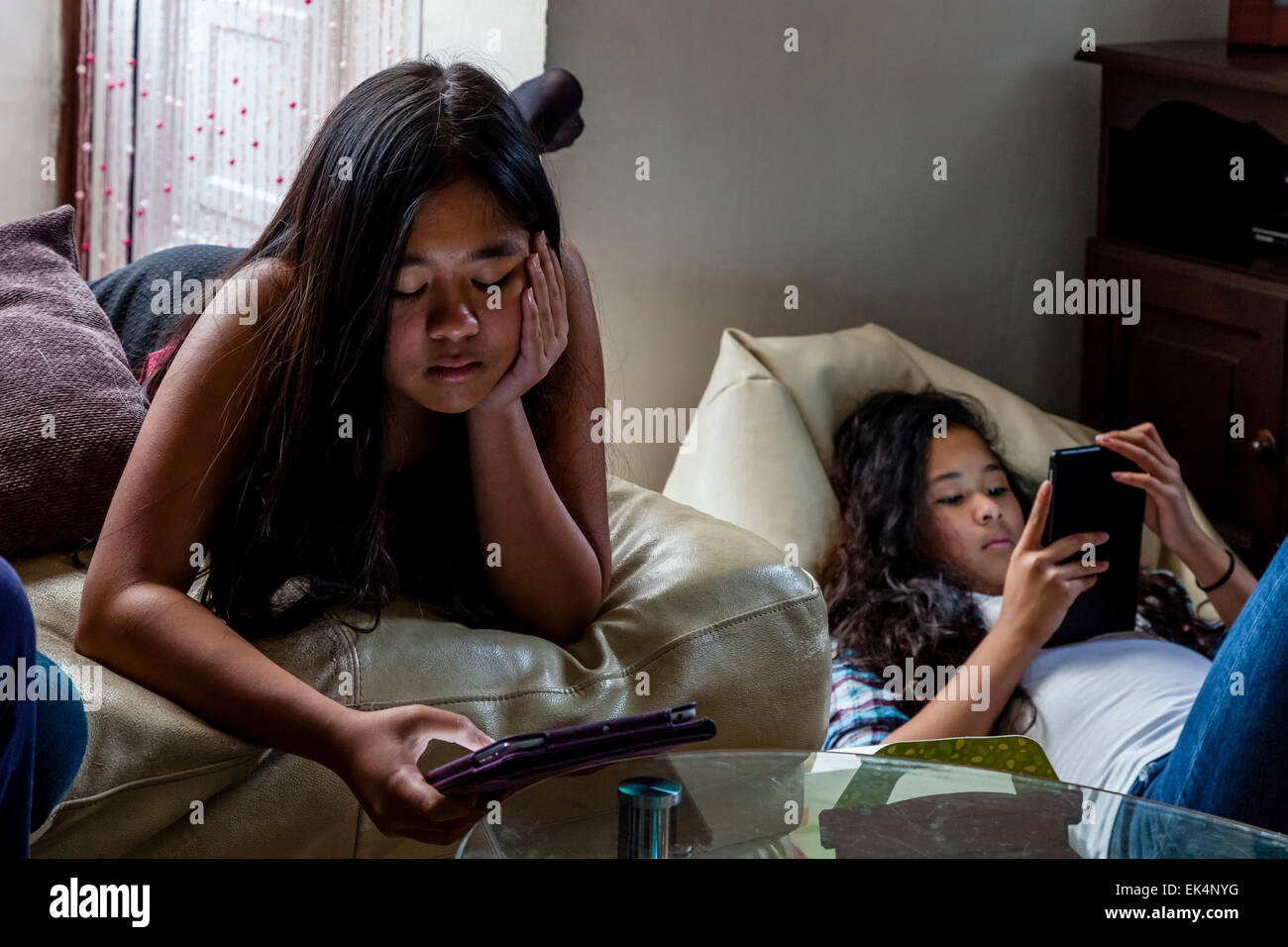 Zwei Mädchen spielen auf Ihren Ipads/Tabletten, Sussex, UK Stockfoto