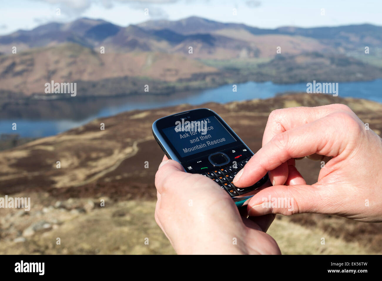 Konzept-Bild von einer Person mit einem Mobiltelefon in den Bergen zum Anruf aus einem Mountain Rescue Team Seenplatte Cumbria UK Stockfoto