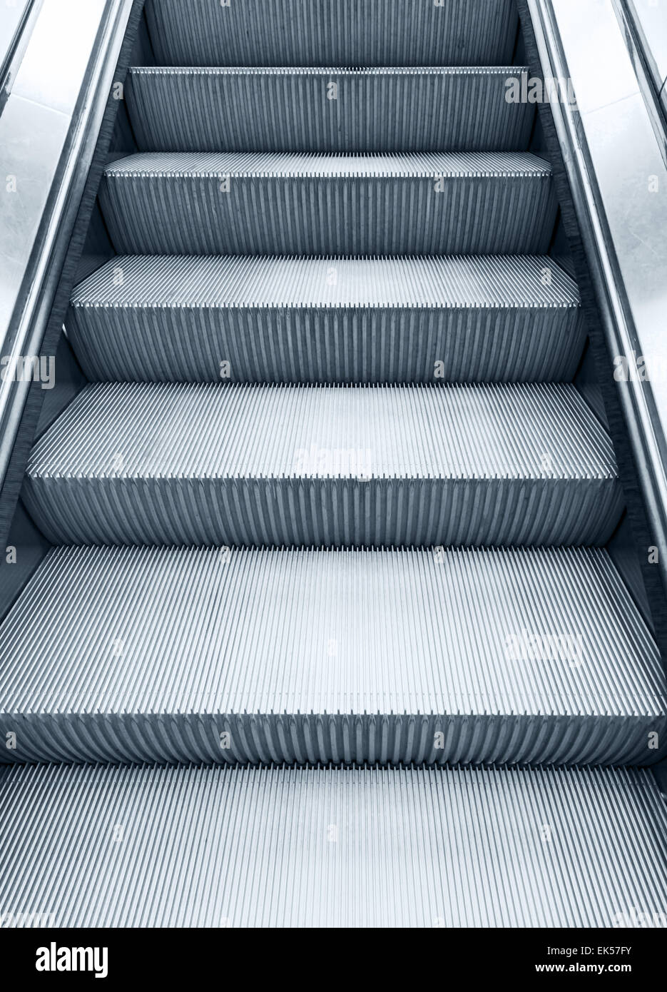 Glänzende Metall Rolltreppe hinauf bewegen, vertikale monochrome Foto mit blauen Tönung Filterwirkung Stockfoto