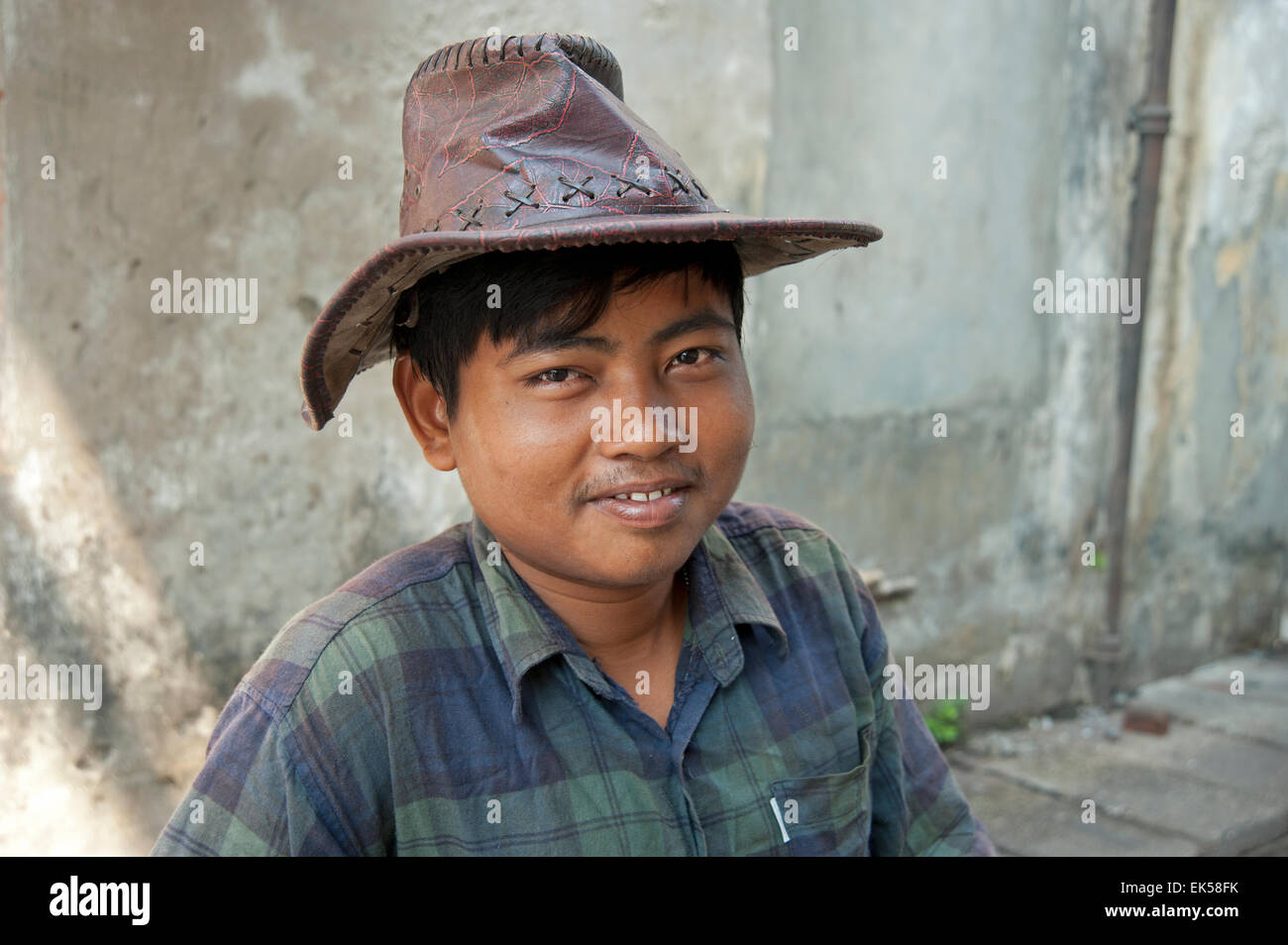 Porträt eines glücklich lächelnde birmanischen mit braunem Leder Hut suchen entspannt gegen einen einfachen Stein Wand Yangon Myanmar Stockfoto