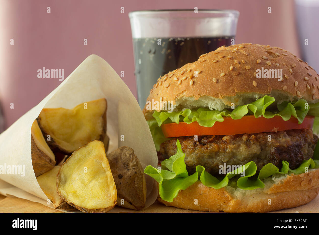 Schuss von Burger, Kartoffelspalten und Cola auf horizontale Holzplatte Stockfoto