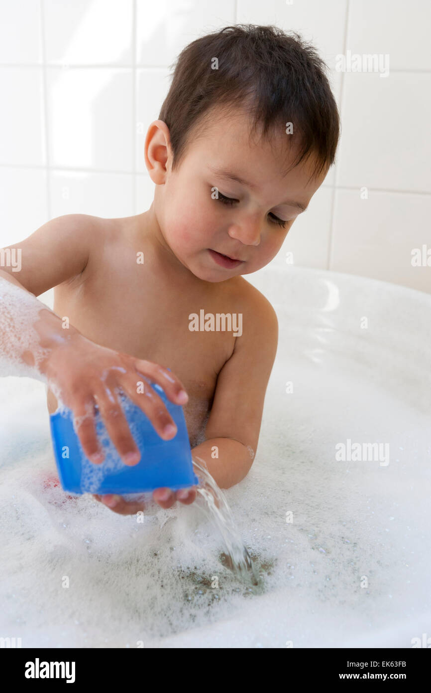 Zwei Jahre alten Jungen in der Badewanne mit Wasser spielen Stockfoto