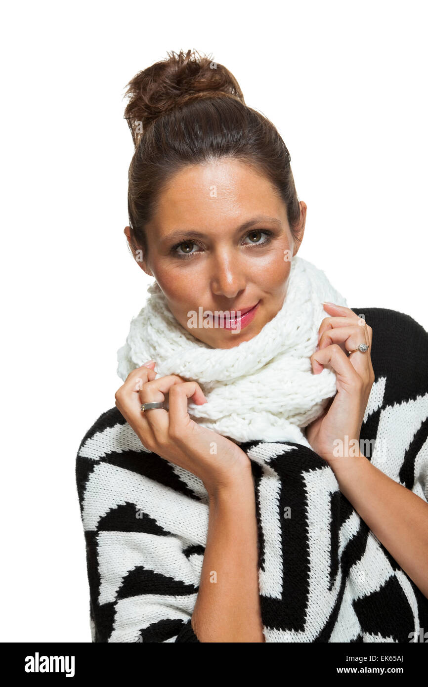 Attraktive elegante Frau in Wintermode kuscheln sich in ihren weißen Schal und schwarzen und weißen Pullover zur Abwehr von kaltem w Stockfoto