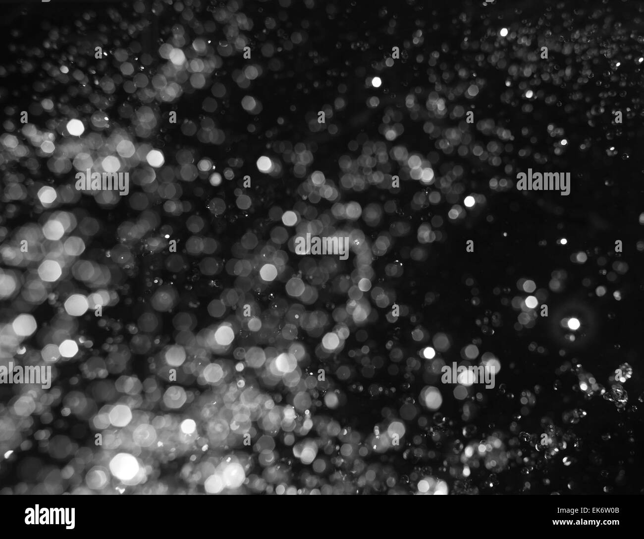 Bokeh leuchtet auf schwarzem Hintergrund, defokussierten Schuss von Wassertropfen in der Luft schwebend fliegen Stockfoto