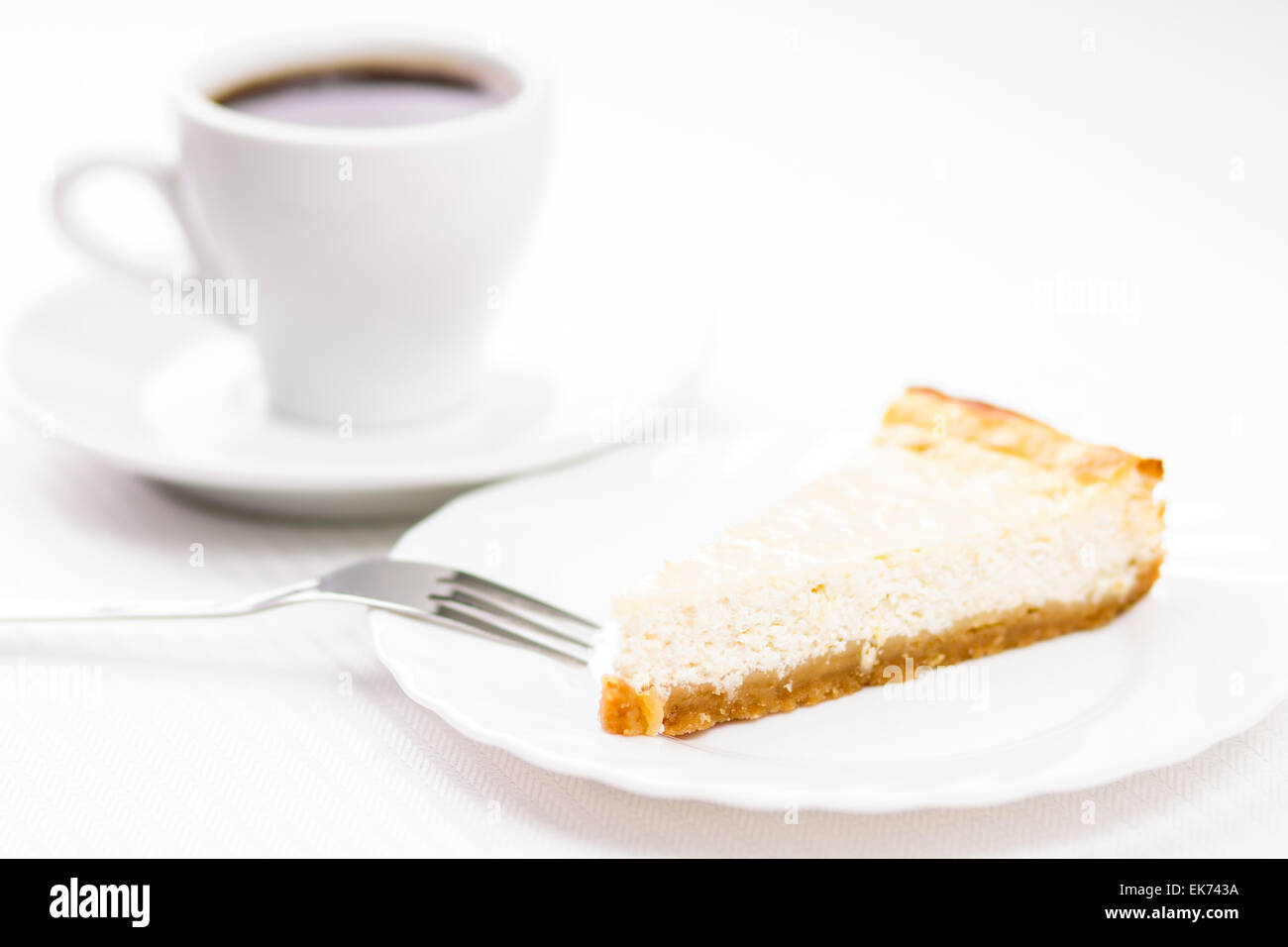 Stück frisch gebackenen Käsekuchen mit Tasse Kaffee auf weißen Tisch espesso Stockfoto