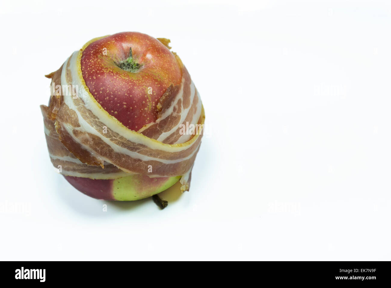 Konzeptbild über falsche Versprechungen von Diäten in der Ernährungsindustrie vertreten durch Streifen Speck umwickelt einen Apfel Stockfoto