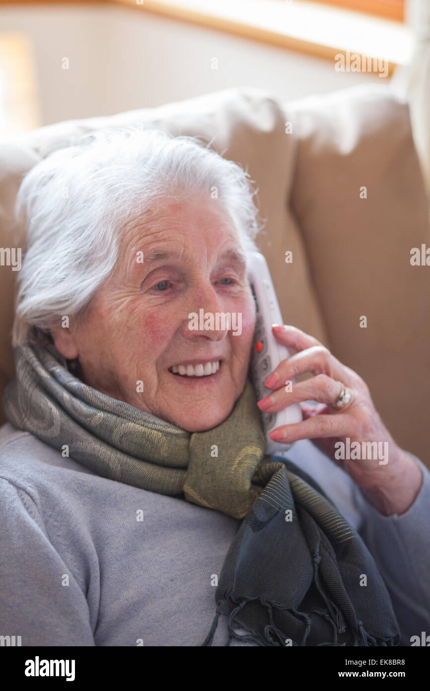 Alte Dame sitzt im Sessel am Telefon sprechen Stockfoto